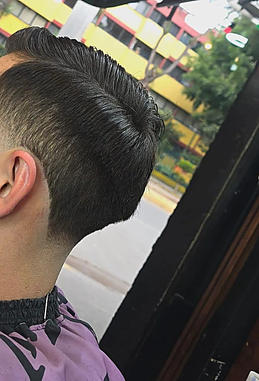 Fade alto con la nuca y la patilla bien marcadas, visto de perfil desde atrás.